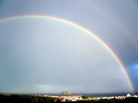 Regenbogen über der Ilhéu da Praia